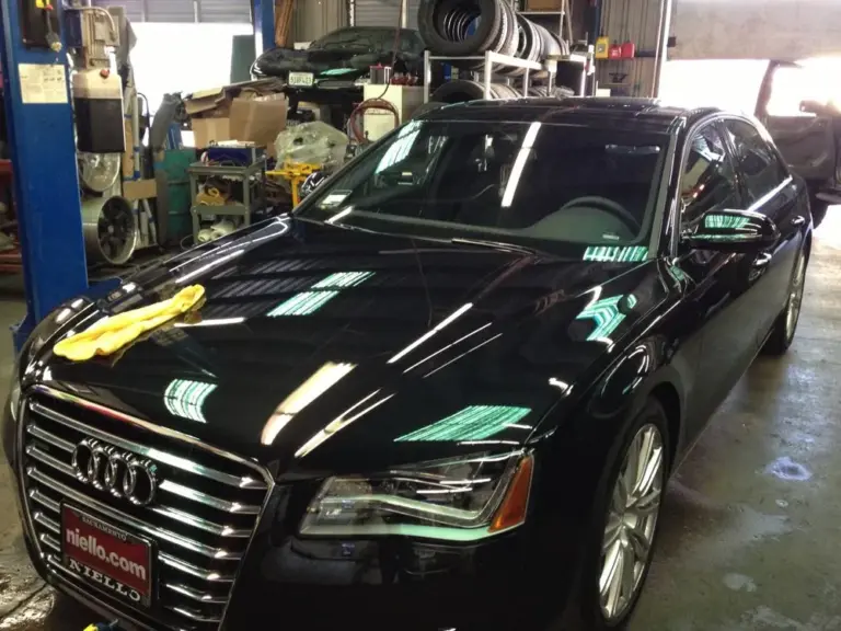 Black Audi A8 with tinted windows, front view, in the shop