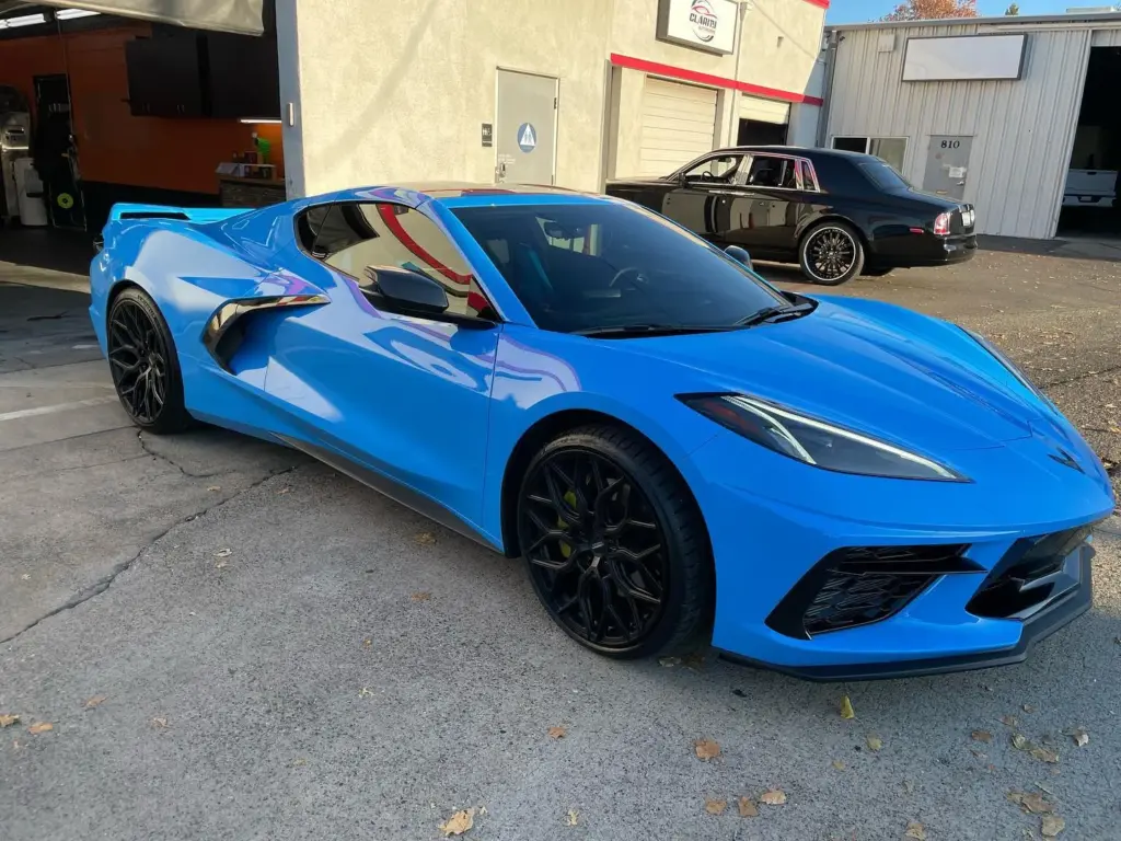 Bright blue C8 Corvette with tinted windows outside the shop