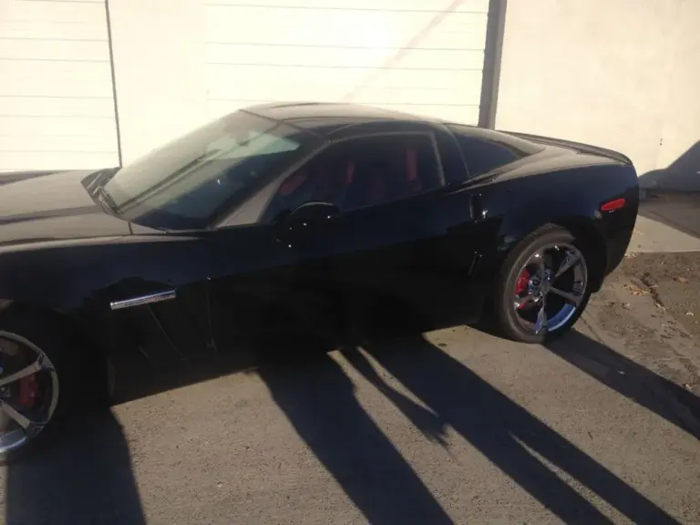 Black Chevrolet Camaro with tinted windows, side view in bright sun