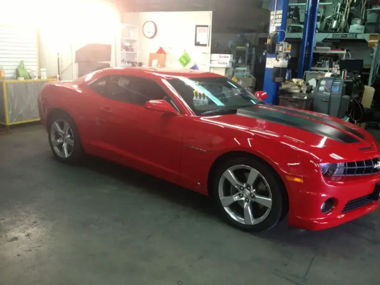 Red Chevrolet Camaro with tinted windows in the shop