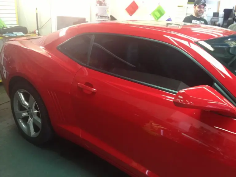 Red Chevrolet Camaro with tinted windows in the shop