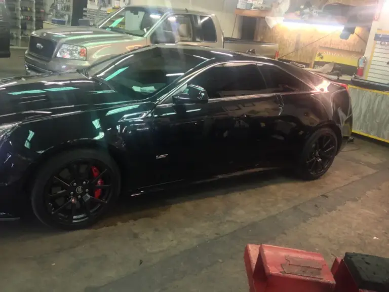 Black Cadillac CTS-V with tinted windows and red brake calipers in the shop