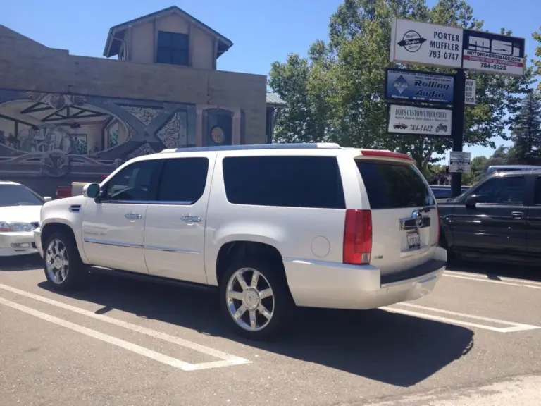 White Cadillac Escalade with dark tinted windows in a parking lot