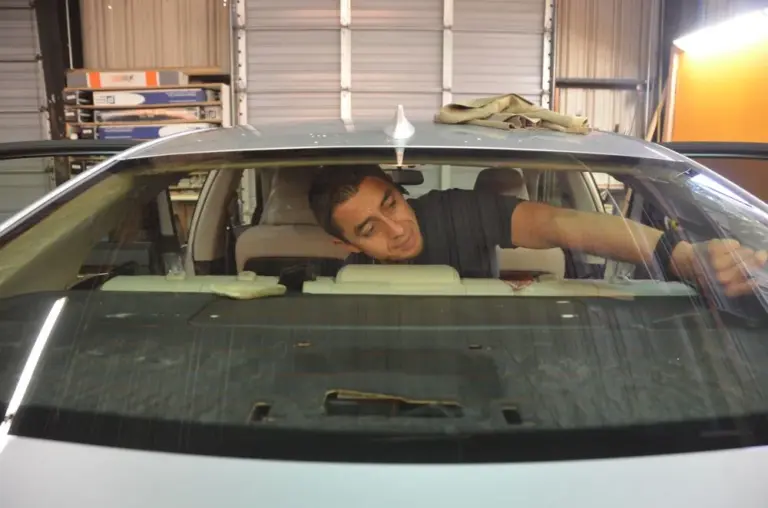 Installer working on a rear window from inside the car