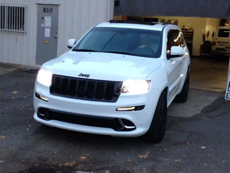 White Jeep Grand Cherokee SRT8 with tinted windows, headlights on