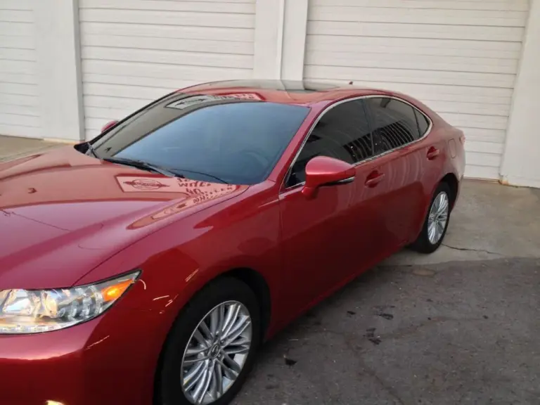 Red Lexus ES with tinted windows in front of the shop's garage doors