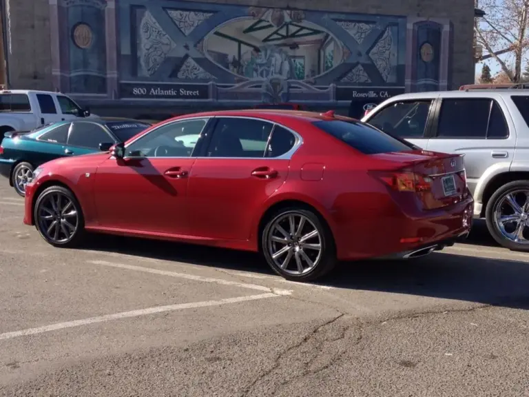 Red Lexus GS with tinted windows by a street mural