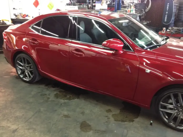 Red Lexus IS with tinted windows, side view, in the shop