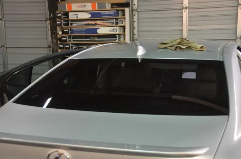 Silver sedan's rear window, freshly tinted, in the shop