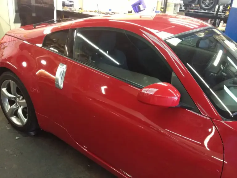 Red coupe's tinted side window, close up