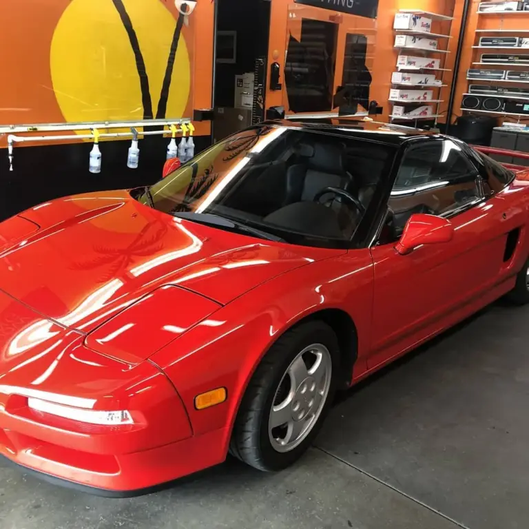 Red Acura NSX with tinted windows inside the orange-walled shop