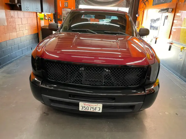 Dark red Chevrolet Silverado with a blacked-out grille in the shop