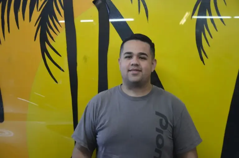 Shades of California team member in front of the yellow palm-tree mural