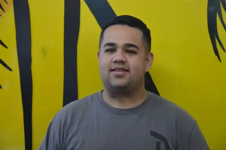 Shades of California team member in front of the yellow palm-tree mural