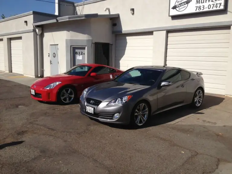 Red Nissan 350Z and gray Hyundai Genesis coupe with tinted windows outside the shop